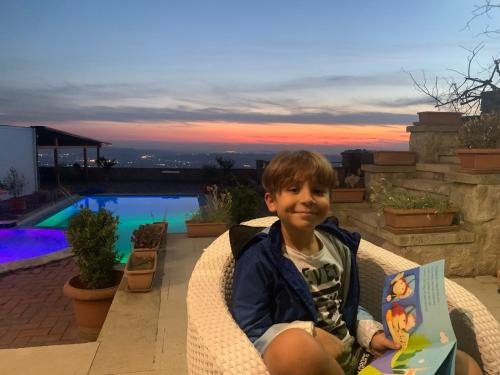 a young boy sitting in a wicker chair holding a book at Villa Celaj “The Castle” in Krujë