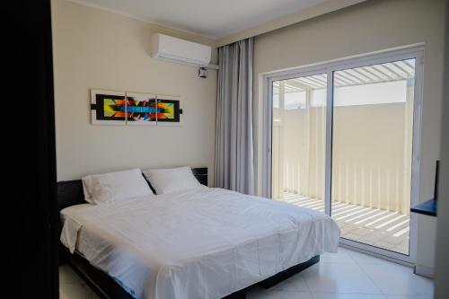 Modern 1-bedroom-apartment 2 km from Eagle beach في شاطئ بالم إيغل: غرفة نوم بسرير وباب زجاجي منزلق