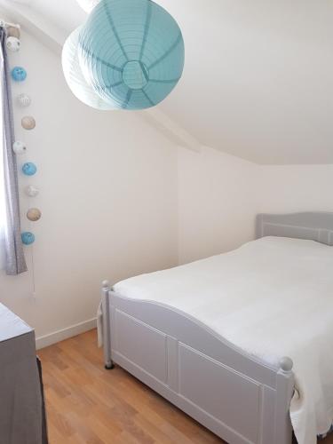 a bedroom with a white bed and a blue fan at Maison au calme, proche centre et mer, jardin clos in Le Croisic