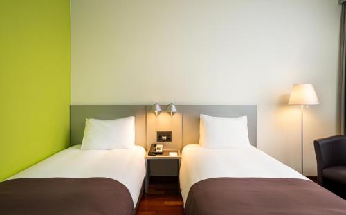 dwa łóżka siedzące obok siebie w pokoju w obiekcie Holiday Inn Zürich Messe, an IHG Hotel w Zurychu