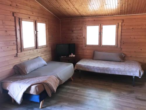 a bedroom with two beds and a tv in a cabin at Retiro Siete Aguas in Siete Aguas