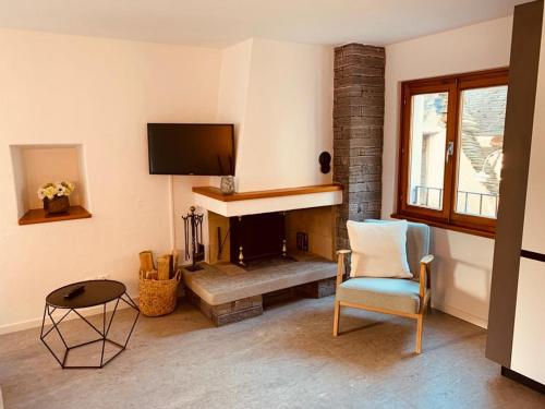 ein Wohnzimmer mit einem Kamin, einem Stuhl und einem TV in der Unterkunft Casa Mille Sassi in Lionza