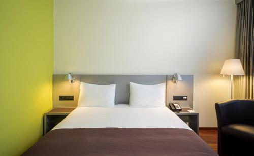 Pokój hotelowy z łóżkiem i krzesłem w obiekcie Holiday Inn Zürich Messe, an IHG Hotel w Zurychu