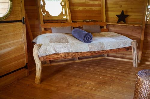 - une chambre avec un lit dans une cabane en rondins dans l'établissement Cabane Perchée dans les Arbres, à Saint-Hilaire-en-Morvan