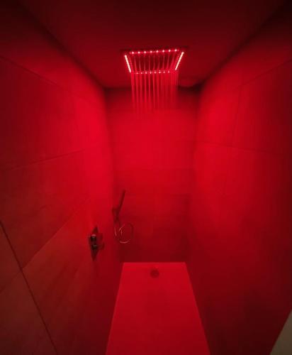 La salle de bains rouge est pourvue d'une douche avec lumière rouge. dans l'établissement L'Evasion chambre DUNE avec sauna et spa privatifs, à Prinquiau