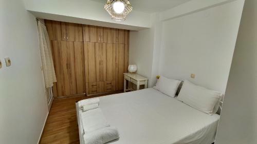 a small bedroom with a white bed and a chair at kostas apartment in Vlikhón