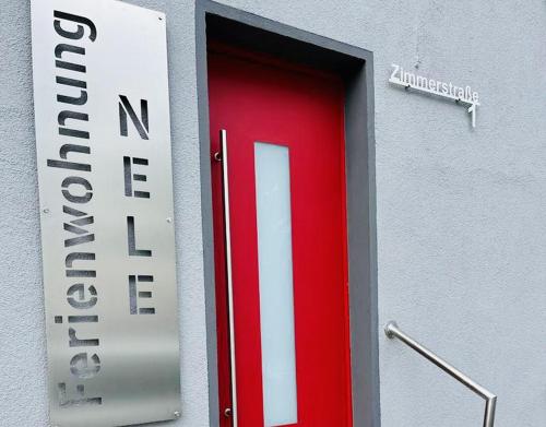 a red door with a sign on the side of a building at Ferienwohnung Nele in Plettenberg