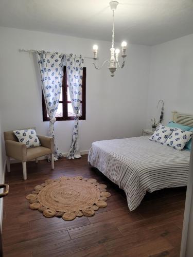 a bedroom with a bed and a chair and a window at Villa La Charlatana in Caleta De Fuste