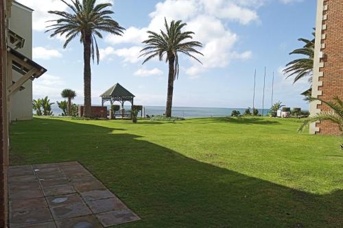 a lawn with palm trees and a gazebo at First Group Brookes Hill Suites in Summerstrand