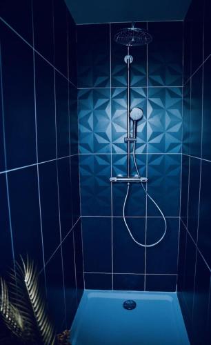 a blue tiled bathroom with a tub with a shower at L'Evasion chambre LAOS avec Jacuzzi privatif in Prinquiau