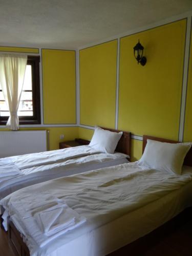 two beds in a room with yellow walls at Недкова къща in Koprivshtitsa