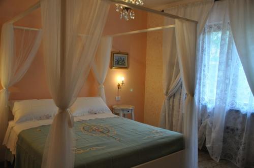 sypialnia z łóżkiem z baldachimem i białymi zasłonami w obiekcie B&B Nonna Luisa w mieście Tarquinia