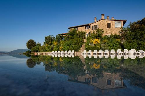 a house on a hill next to a body of water at Il Poggio degli Olivi in Bettona