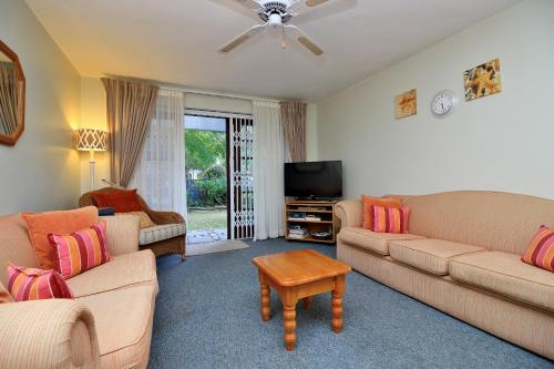 a living room with two couches and a flat screen tv at Pelican Lodge Guesthouse in Sedgefield