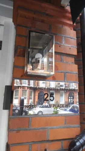 a sign on the side of a brick wall with a window at Regency Hotel Parkside in London