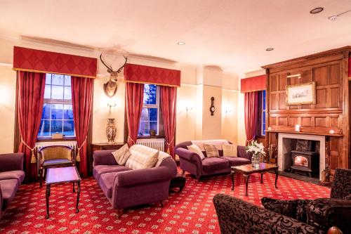 a living room with couches and a fireplace at Dalmunzie Castle Hotel in Glenshee