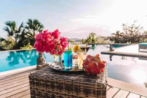 a table with flowers and drinks next to a pool at The Endless Summer Resort in Bumbang