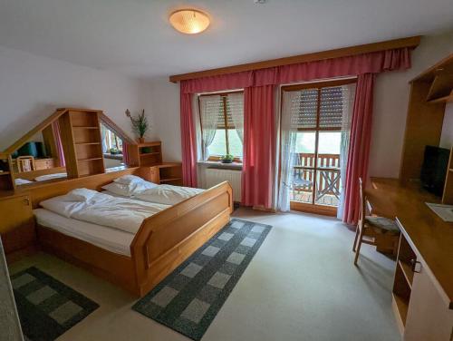 a bedroom with a bed and a desk and windows at Cafe-Bäckerei-Pension Weigl in Oberviechtach
