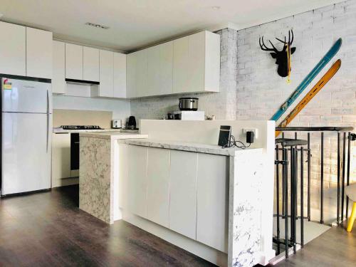 a kitchen with white cabinets and a white refrigerator at Hotham 3 Bedroom Apt - 24 Lawlers in Mount Hotham