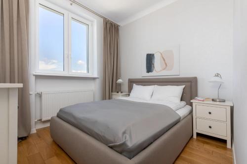 a white bedroom with a bed and a window at ECRU Spacious Premium Apartment with City View in Warsaw WWA4 in Warsaw