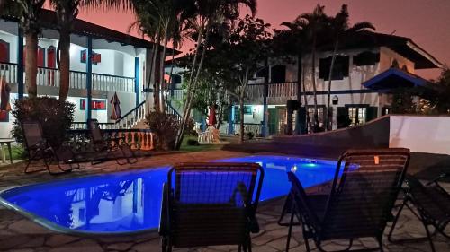 een zwembad 's nachts met stoelen eromheen bij CONDOMINIO COLONIAL APARTAMENTOS 150M DA PRAIA in Bombinhas