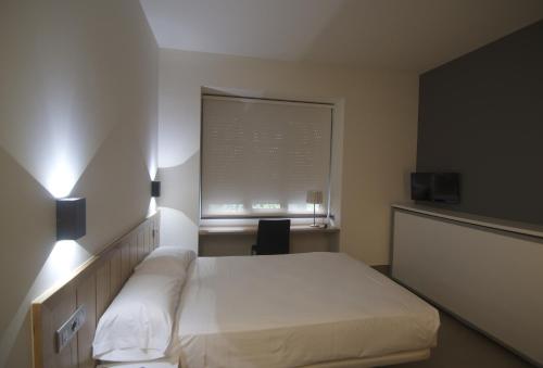 a bedroom with a white bed and a window at The Book Factory Hostel by gaiarooms in Valladolid