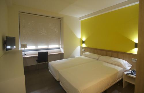 a bedroom with a white bed and a yellow wall at The Book Factory Hostel by gaiarooms in Valladolid