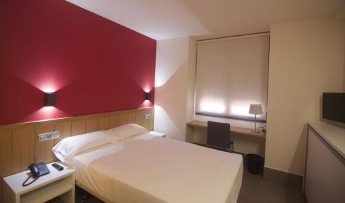 a bedroom with a white bed and a red wall at The Book Factory Hostel by gaiarooms in Valladolid