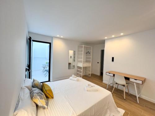 a white bedroom with a bed and a desk at La Cala de Alcalá Luxury in Alcalá