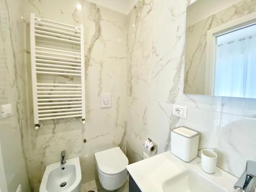 a white bathroom with a toilet and a sink at IL VIAGGIATORE RELAIS SUL MARE in Gaeta