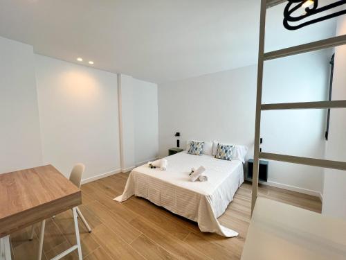 a white bedroom with a bed and a table at La Cala de Alcalá Luxury in Alcalá