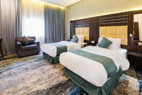 a hotel room with two beds and a chair at White Diamond Hotel Sari in Jeddah
