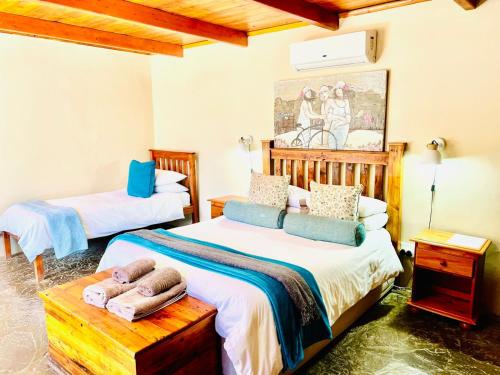 a bedroom with two beds and a painting on the wall at Travalia Guest Farm in Nelspoort