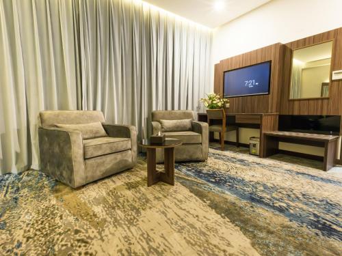 a living room with two chairs and a television at White Diamond Hotel Sari in Jeddah