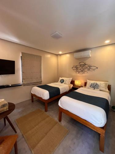 a room with two beds and a tv at Southseas Beach Resort and Dive Center in Santander