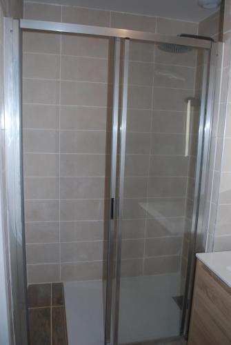 een douche met een glazen deur in de badkamer bij gite de la barthe in Garrey