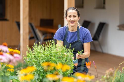 a woman in an apron standing next to a flower garden at Pircherhof - Adults Only am Biobauernhof in Pöllau