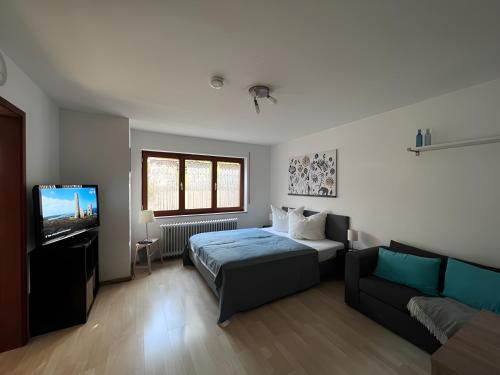 a bedroom with a bed and a couch and a television at Ferienwohnung Coco in Schallstadt