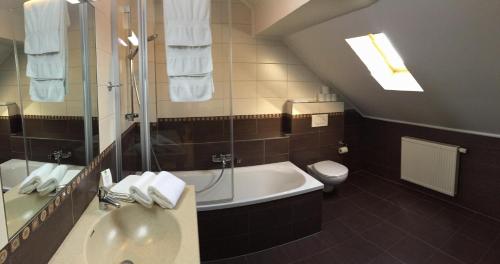 ein Badezimmer mit einem Waschbecken, einer Badewanne und einem WC in der Unterkunft Hotel Pax in Luxemburg (Stadt)