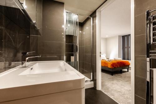 a bathroom with a bath tub and a bedroom at Victoria Place - 3-bed apartment, parking, Wi-Fi in Hyde