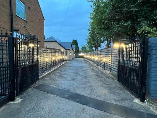 a driveway with a fence with lights on it at Modern 4 Bedroom Stylish Villa with out-door Hot Tub in Quinton