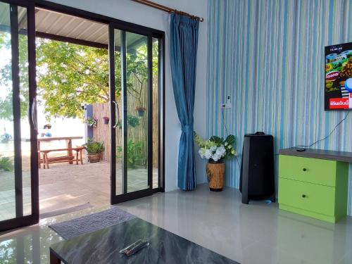 ein Wohnzimmer mit einem TV, einer Kommode und einer Glasschiebetür in der Unterkunft Villa loved beach AO NAM MAO 2 in Ao Nam Mao