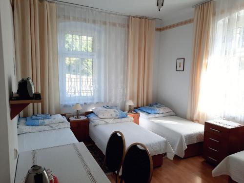 a bedroom with three beds and a window at Ośrodek Wypoczynkowy Buenos Aires in Kudowa-Zdrój
