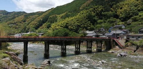 un train traversant un pont sur une rivière dans l'établissement そらやまゲストハウス Sorayama guesthouse, à Ino