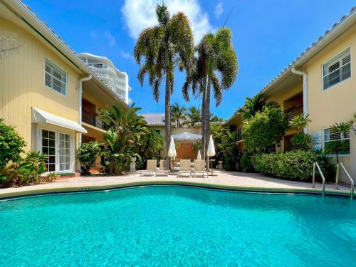 a swimming pool in front of a house with palm trees at La Casa Hotel in Fort Lauderdale