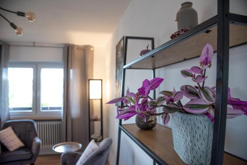 a vase with purple flowers on a shelf in a room at Ferienwohnungen Hopfen und Malz in Fichtelberg