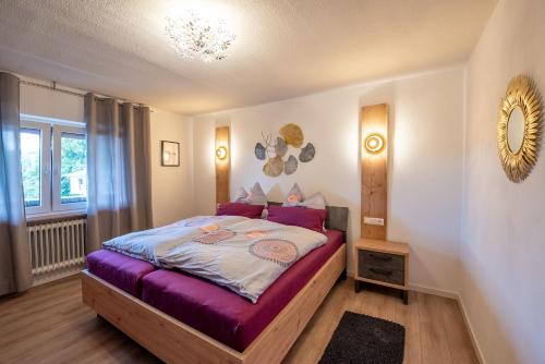 a bedroom with a bed with purple sheets and a mirror at Ferienwohnungen Hopfen und Malz in Fichtelberg
