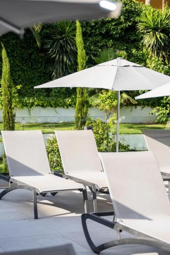 a row of white chairs and an umbrella at INNSiDE by Meliá Palma Bosque in Palma de Mallorca
