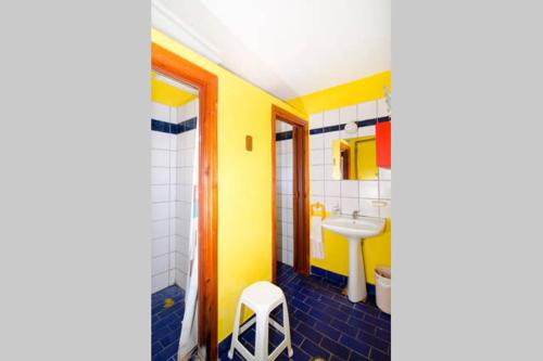 a yellow bathroom with a sink and a stool at Summit Zero Hostel in Plaka Litochorou