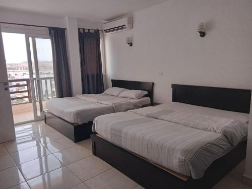 Jasmine Resort & Aqua park في شرم الشيخ: سريرين في غرفة الفندق مع شرفة